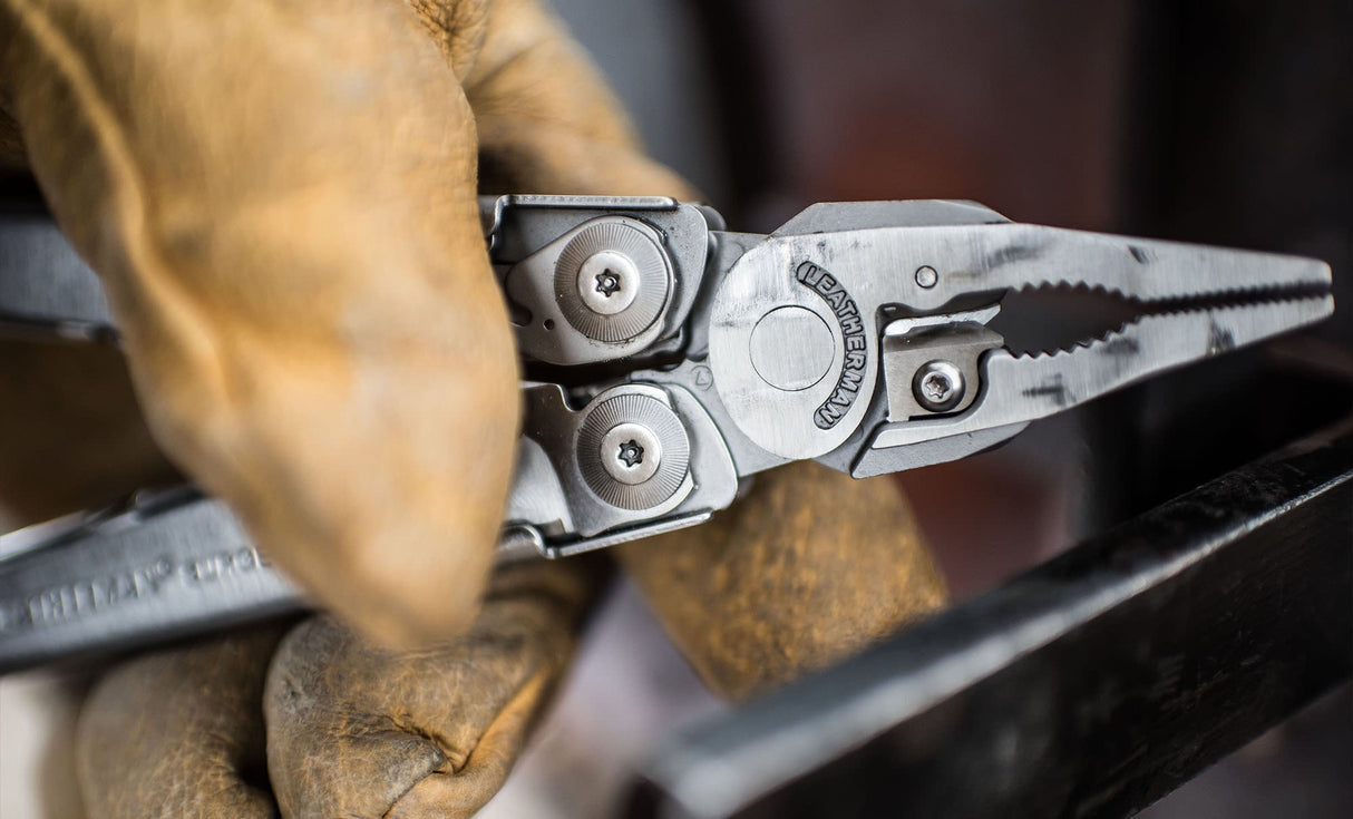 Translation missing: es.Close up of a hand holding stainless steel Leatherman Surge® multitool with pliers and gloves