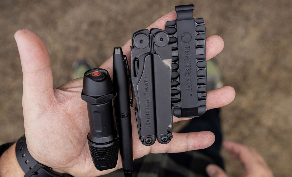 Translation missing: es.Hands showcasing a Black Leatherman Wave® Plus, bit kit, pen, and flashlight
