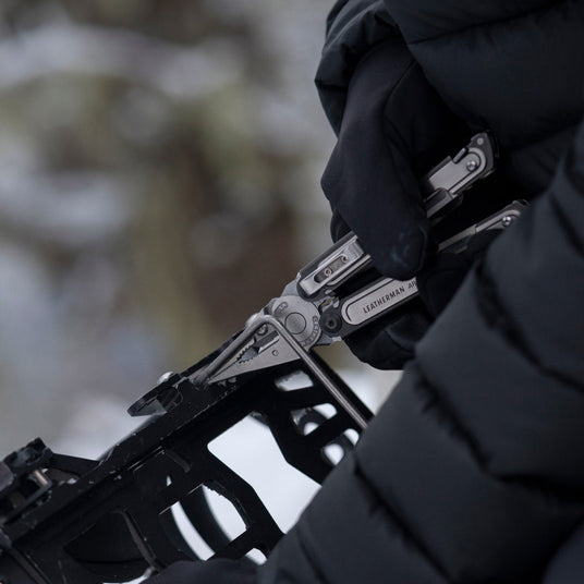 Translation missing: fr.Someone using the pliers on a Leatherman ARC to fix a binding on a snowboard