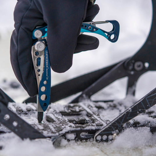Translation missing: fr.Someone using a Skeletool CX to tighten the binding on a snowboard