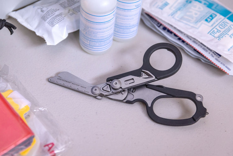 A black Raptor Rescue laying on a table surrounded by medical supplies showing it's shears.