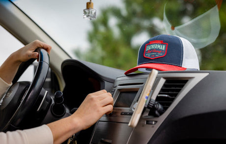 Translation missing: fr.Person driving a car with a Leatherman Pacific Northwest Trucker hat on the dashboard