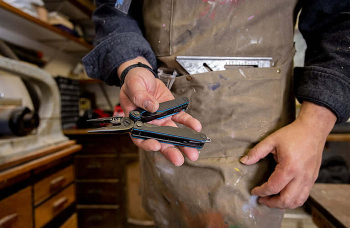 Translation missing: pl.Person holding an older Leatherman multitool in a workshop, showcasing its features and design