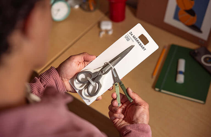 Translation missing: de.Person using the scissors on a Leatherman Micra in cardamom color to cut the zip ties on a package