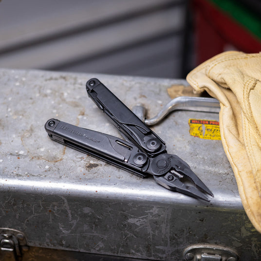 Translation missing: nl.A black Leatherman Surge rests on a metal tool box, showcasing its compact design and versatility