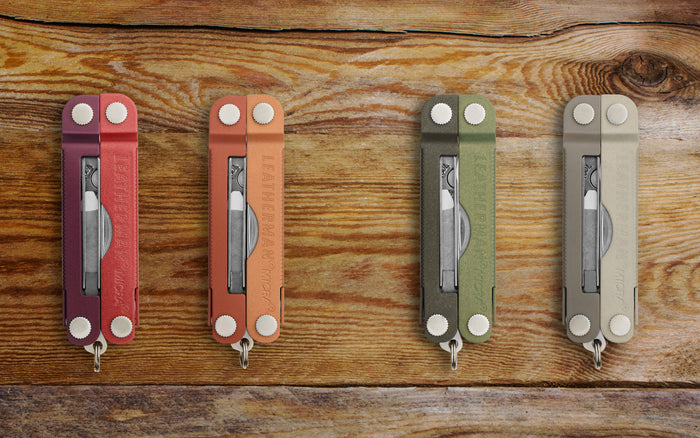 Translation missing: en.Four stylish Leatherman Micra in fall colors - Mulled Wine, Pumpkin Spice, Spruce, and Winter Fog - arranged on a wooden background