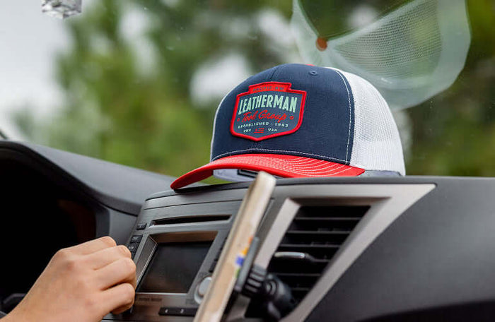 Translation missing: pl.Leatherman Pacific Northwest hat resting on car dashboard, showcasing its stylish design and vibrant colors against a blurred natural background
