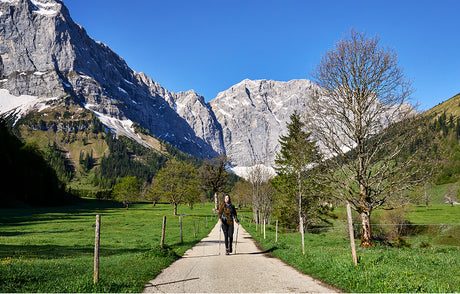 Translation missing: it.Female hiker walking along a picturesque mountain trail, immersed in nature