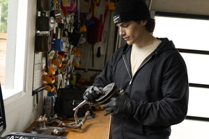 Translation missing: de.A person wearing a black Leatherman Vintage Beanie working on a car part in a garage