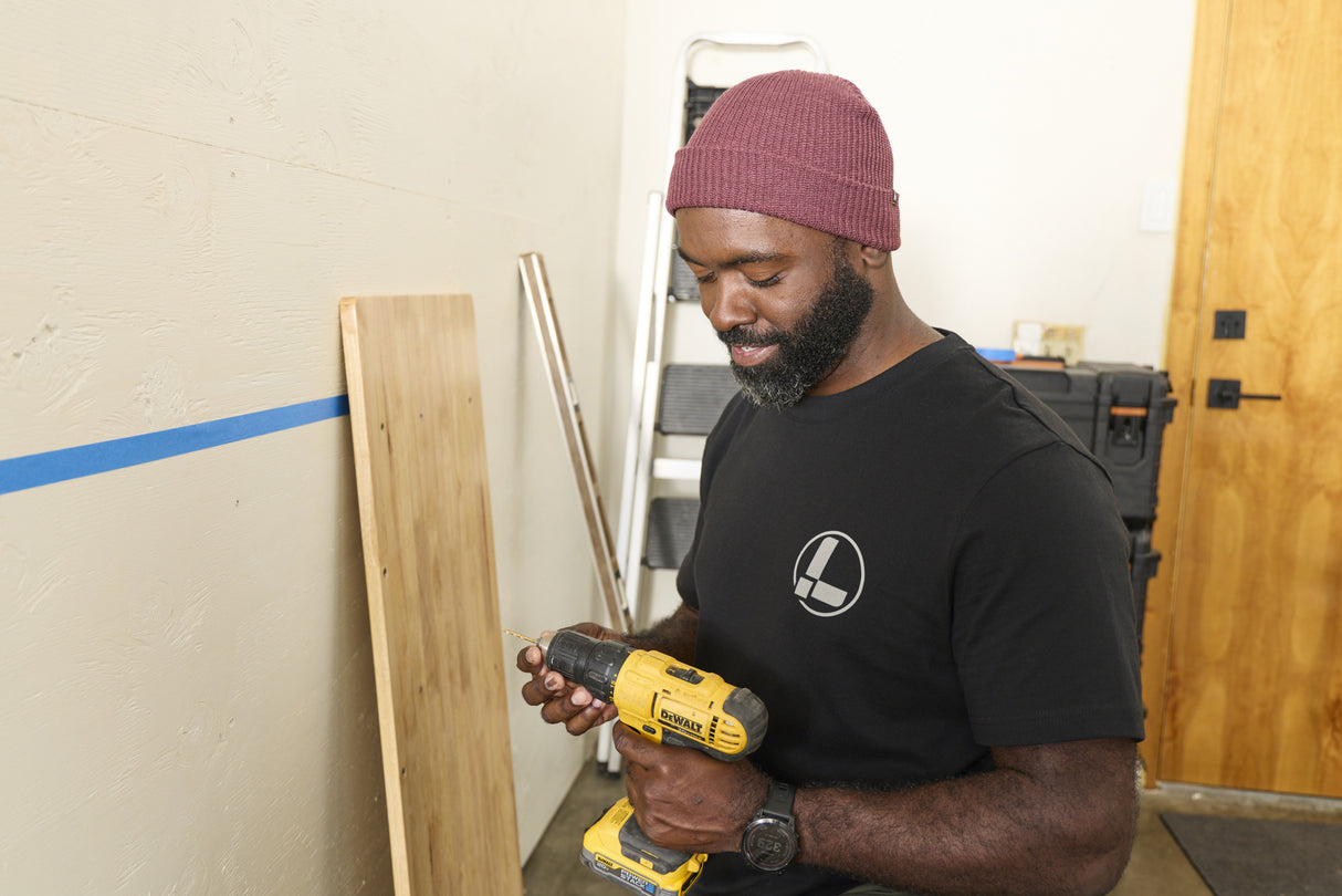 Translation missing: es.A person wearing a black Leatherman Classic Tee holding a yellow power drill while working indoors