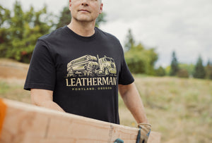 Translation missing: fr.A person wearing a black Leatherman Timber Tee carrying a wooden board outdoors