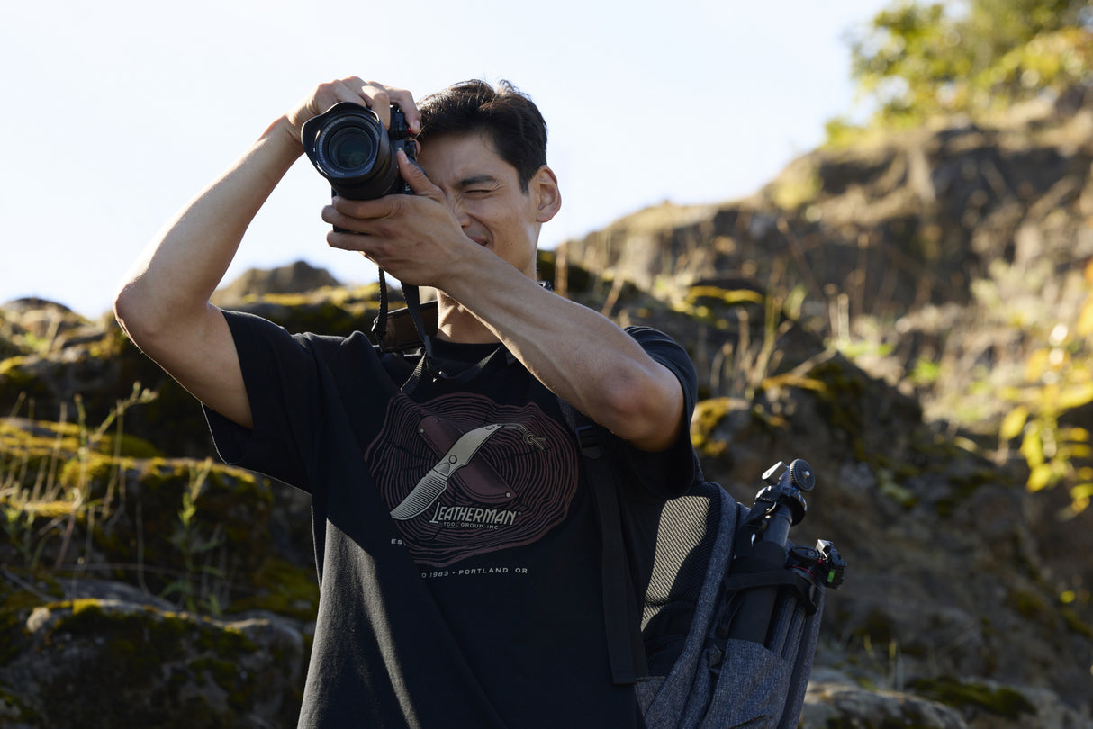 Translation missing: es.A photographer wearing a black Leatherman Blade &amp; Grain Tee while taking a pictures outdoors