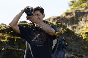 Translation missing: es.A photographer wearing a black Leatherman Blade &amp; Grain Tee while taking a pictures outdoors