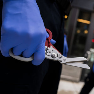 Translation missing: es.A nurse grasping a Leatherman Garnet Raptor Rescue with shears showing, ready to use