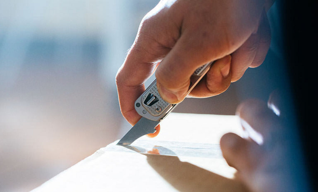 Man using box opener on Leatherman T2 to open brown box