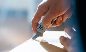 Man using box opener on Leatherman T2 to open brown box