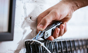 Man using scissors on Leatherman T4 to cut zip ties holding black wire cube walls