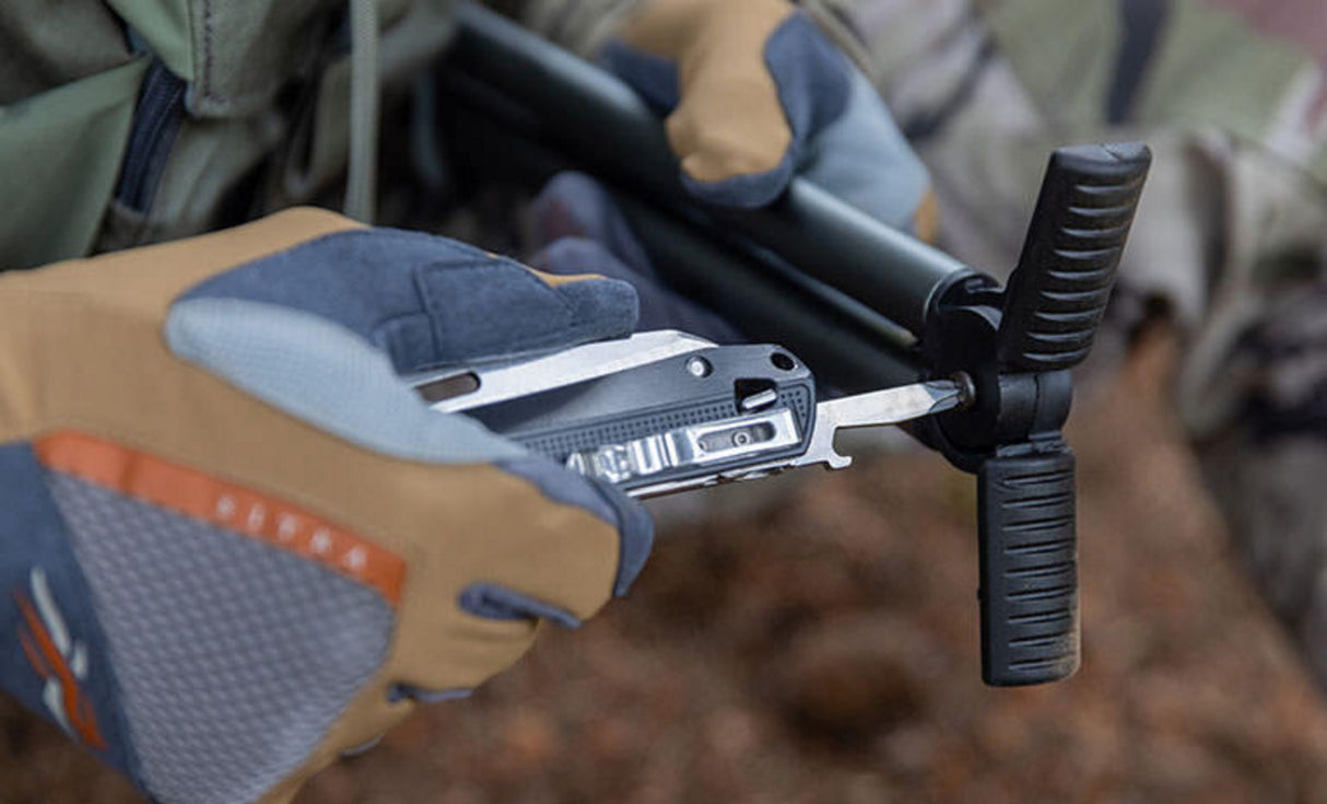 Man in green jacket and tan brown leather gloves using phillips screwdriver on Leatherman K4