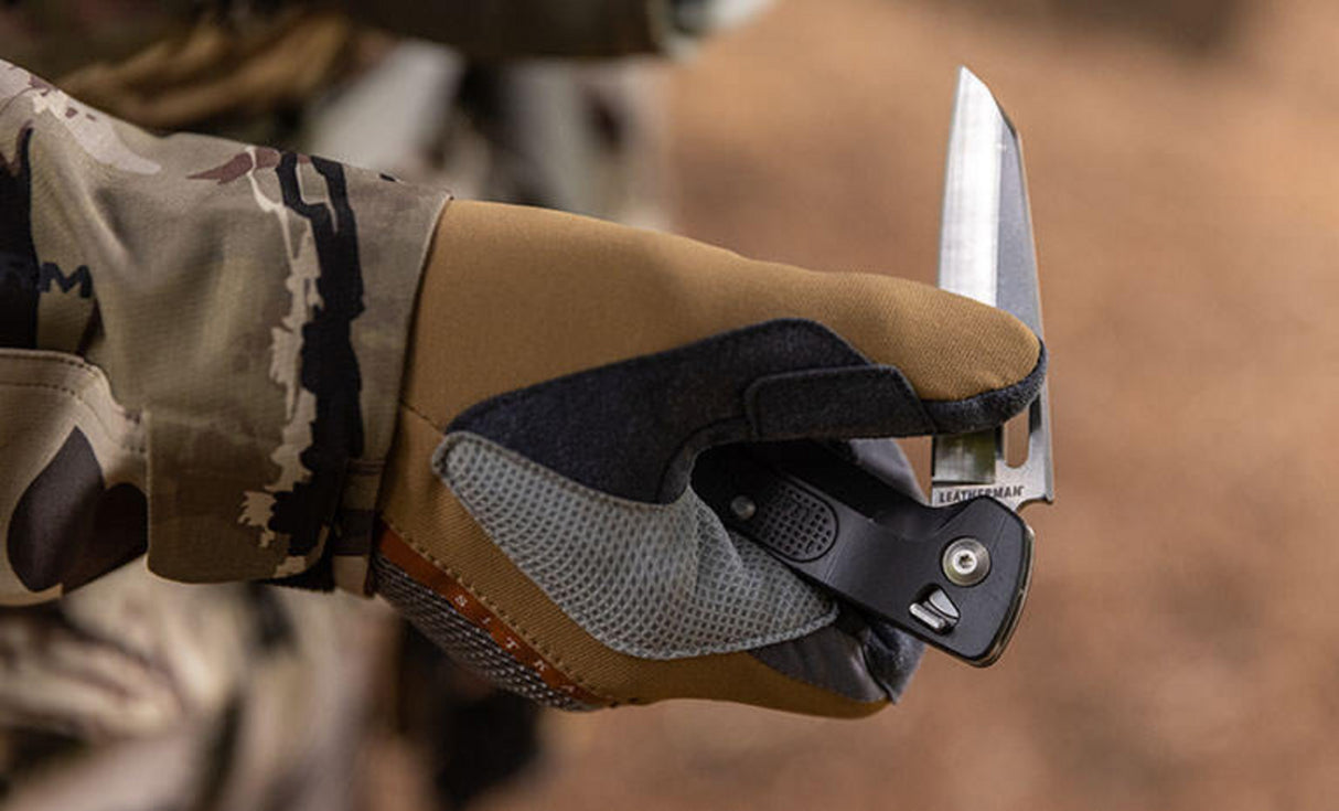 Man wearing camo jacking and tan brown leather gloves opening a Leatherman K4