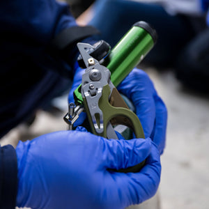 Translation missing: es.A nurse wearing blue gloves uses the oxygen tank wrench on a Leatherman Woodland Raptor Rescue to open an oxygen tank