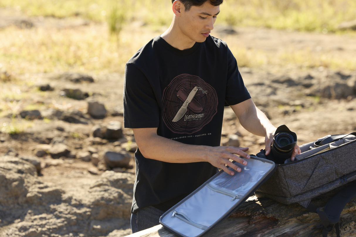 Translation missing: es.A person wearing a black Leatherman Blade &amp; Grain tee pulling a camera out of a camera pack