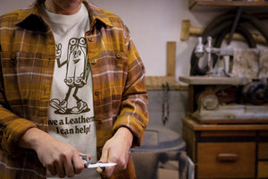 Translation missing: es.A person wearing a natural-colored Leatherman Mr. Wave Tee with a cartoon multitool design using a Leatherman multitool to sharpen a pencil