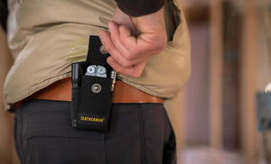 Man opening black nylon Leatherman sheath carrying flashlight, Leatherman tool, and Leatherman ratchet driver