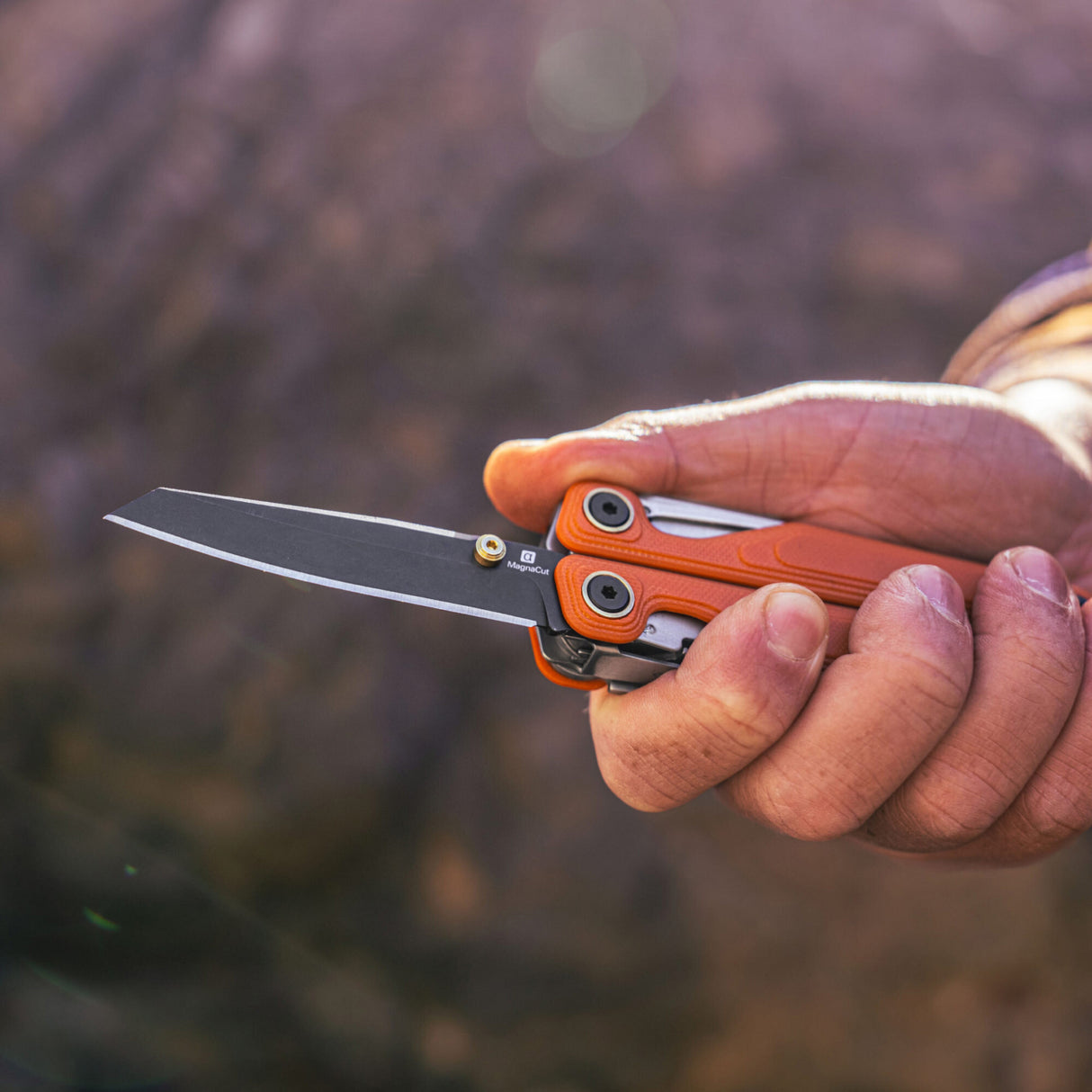 Translation missing: de.Person holding the Leatherman Wave® Alpha Canyonland multi-tool with knife blade open outdoors