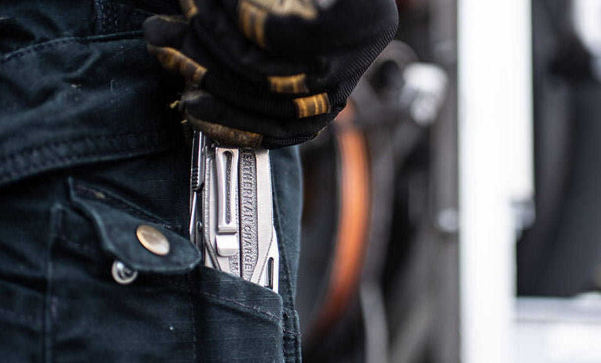 Man with dirty black and yellow gloves pulling Charge+ TTI out of back jean pocket