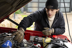 Translation missing: de.A person wearing a black Leatherman Vintage Beanie working under the hood of a red vehicle