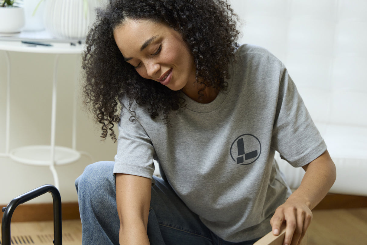 Translation missing: en.A person wearing a gray Leatherman Classic Tee using a Wave Alpha in Cascadia color to assemble a small table showcasing the Leatherman logo on the chest