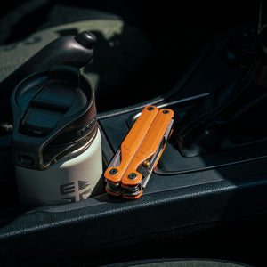 Translation missing: de.Leatherman Wave® Alpha Canyonland multi-tool folded, placed in a vehicle cup holder beside a travel mug