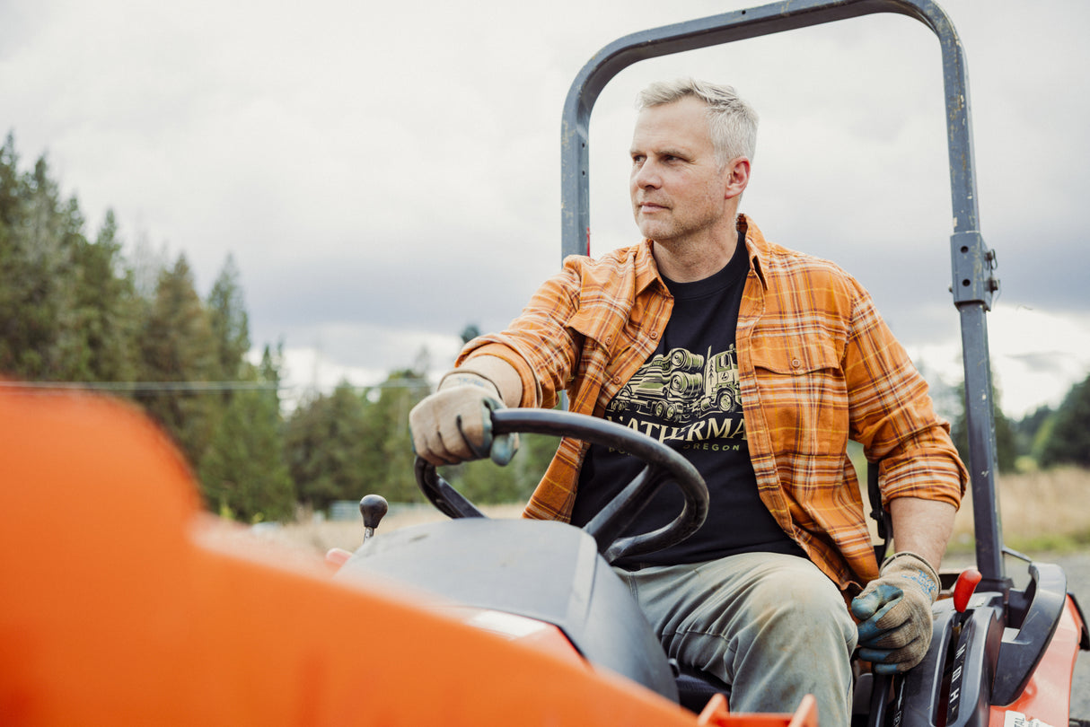 Translation missing: fr.A person wearing a black Leatherman Timber Tee driving a tractor outdoors