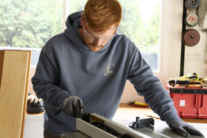 Translation missing: en.A person wearing a storm blue Leatherman Classic Hoodie working in a bright workshop