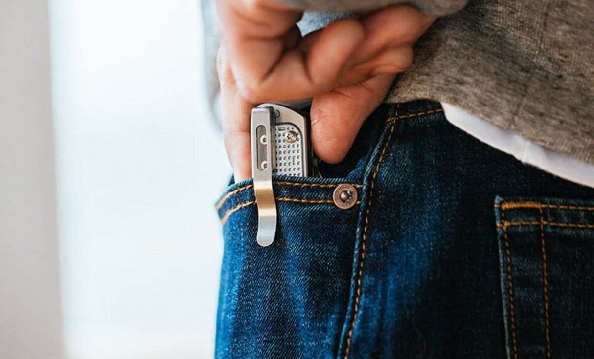 Man in white tee, gray sweatshirt, blue jean pulling Leatherman T2 from front jean pocket