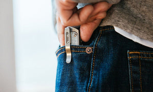 Man in white tee, gray sweatshirt, blue jean pulling Leatherman T2 from front jean pocket