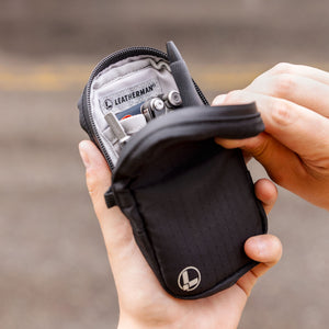 Translation missing: fr.Hands opening a black Leatherman tool pouch filled with multitools and accessories