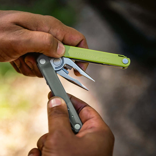 Translation missing: da.A close-up of hands holding the Mossy Slate Leatherman Bond® multitool, showcasing its sleek design and functionality