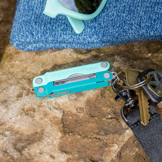 Translation missing: da.Leatherman Parakeet Micra® multitool on a rock next to sunglasses and keys, showcasing its compact design