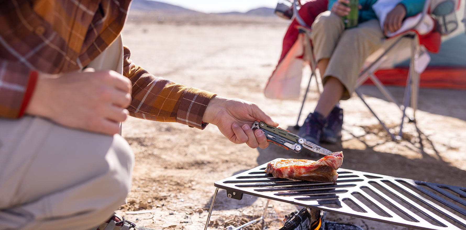 Signal® Tundrascape Limited Edition multitool flipping a steak on a camp grill at a desert campsite