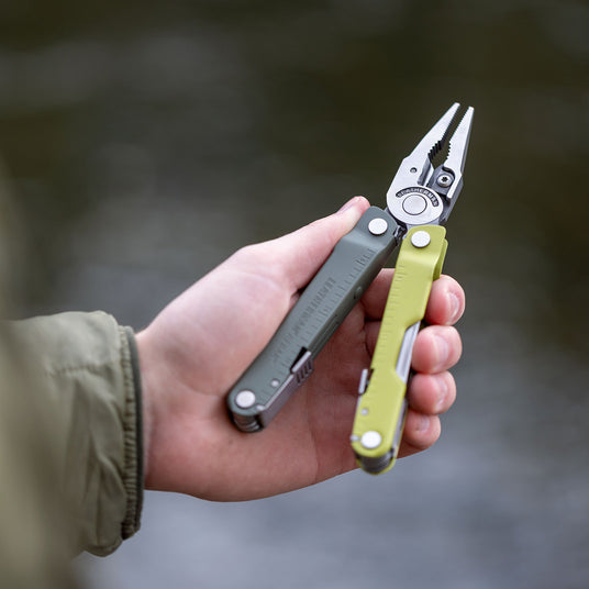A close-up of a person holding a green Leatherman Rebar, highlighting its compact design and multiple functionalities.