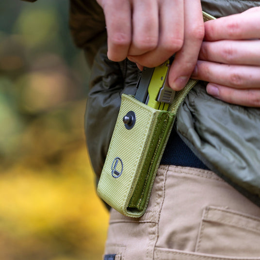 A close-up of a person’s hand gripping a green Leatherman Rebar, highlighting its portability and color.