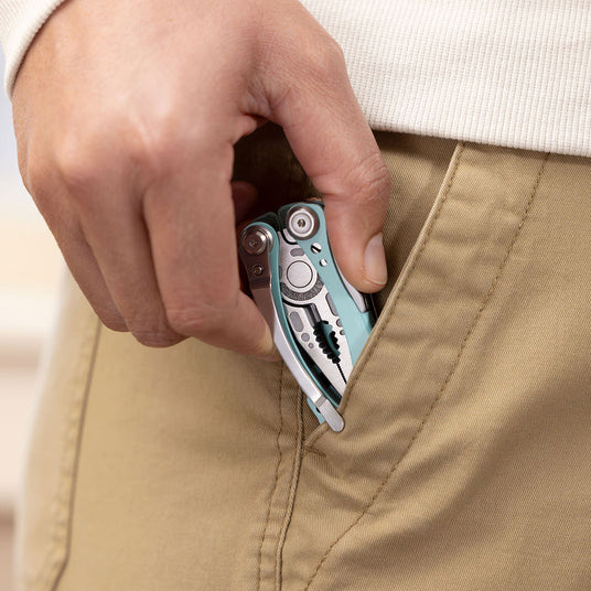 A hand holding a Leatherman Skeletool, partially concealed in a pocket, suggesting utility and everyday carry.