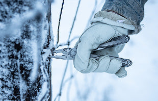 Translation missing: nl.A person in gloves holds a pair Leatherman Charge+ TTi, preparing to cut something with focused attention