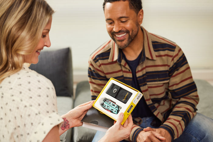 Translation missing: de.A man and woman sit on a couch, joyfully opening a Leatherman Signal gift together