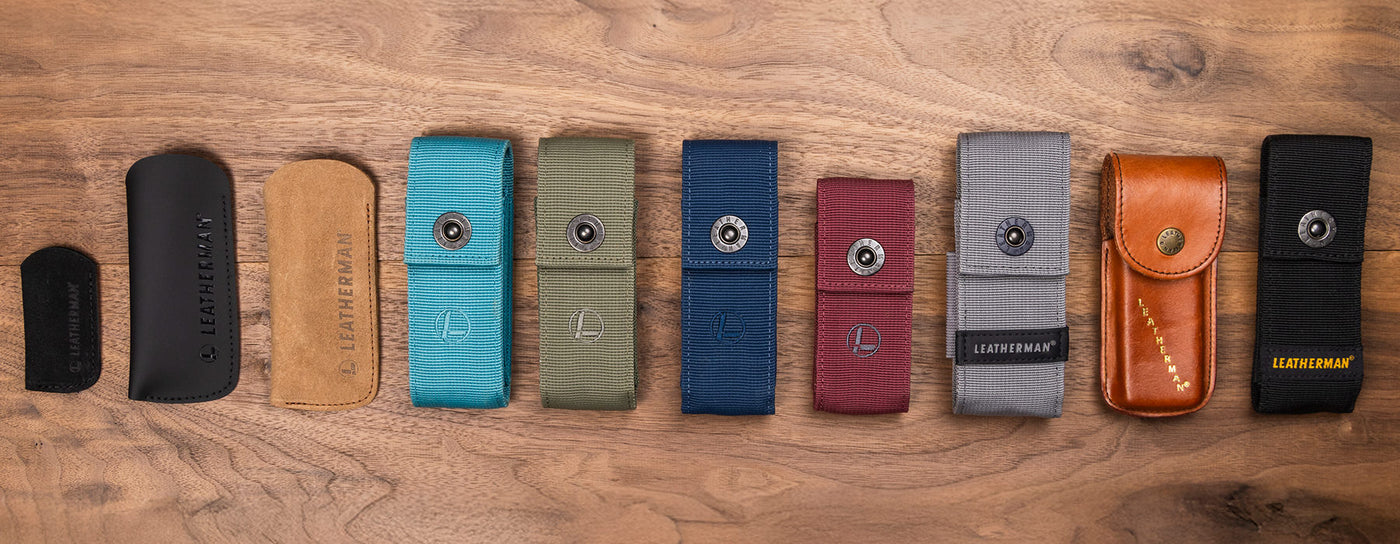 Translation missing: de.A top-down view of ten different Leatherman tool pouches arranged in a row on a wooden surface. The pouches vary in size, material, and color, including black, tan, blue, green, navy, red, gray, brown leather, and black nylon. Some feature snap closures and Leatherman logos, highlighting the variety of carrying options available for multitools