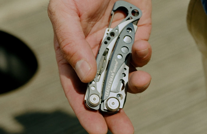 Translation missing: pl.A person holding a Leatherman Skeletool® multi-tool in hand, showcasing its sleek metallic design