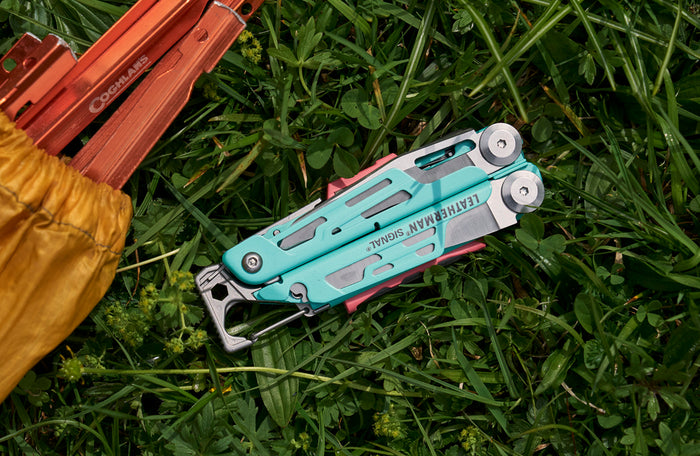 Translation missing: pl.Aqua Leatherman Signal® multi-tool resting on lush green grass, showcasing its vibrant color and design
