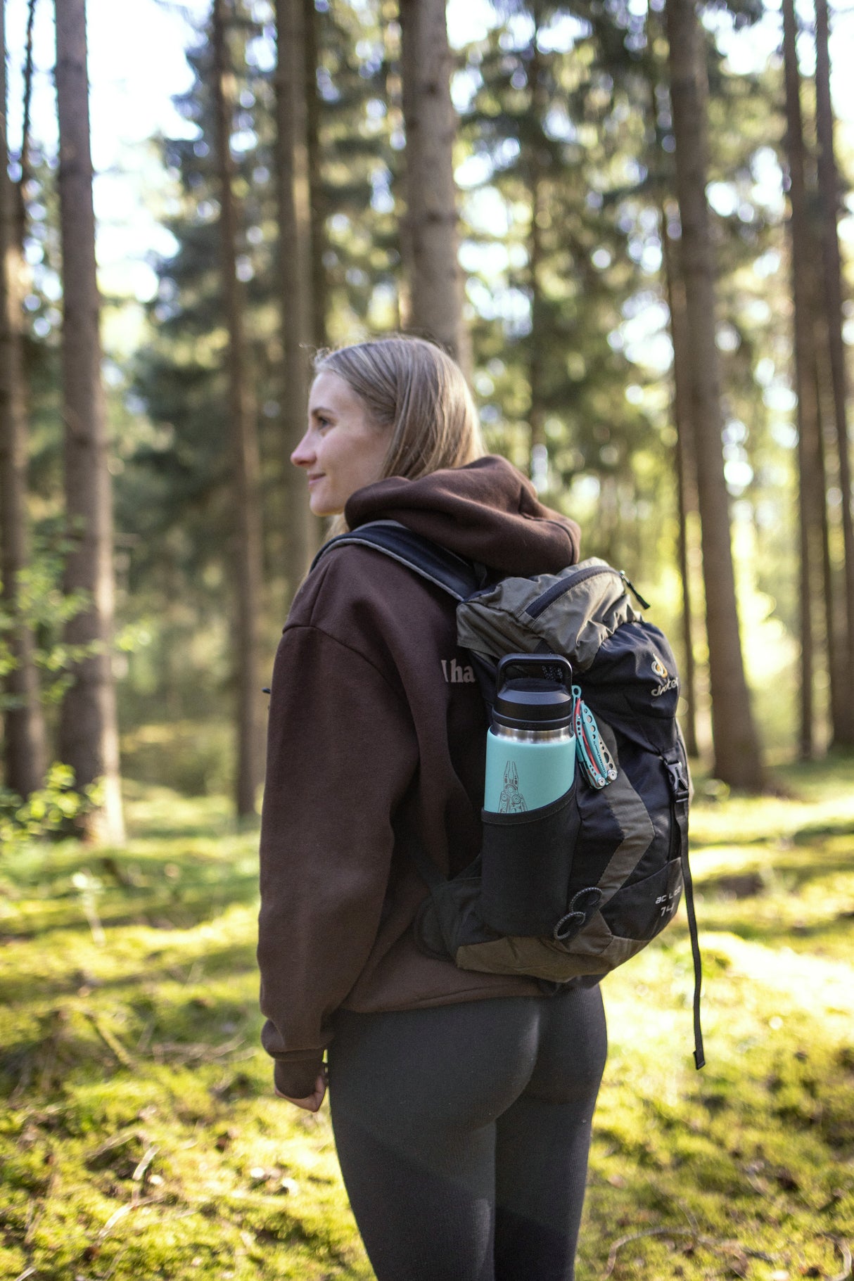 Translation missing: pl.Hiker in a forest carrying a backpack with a mint green Yeti bottle in the side pocket