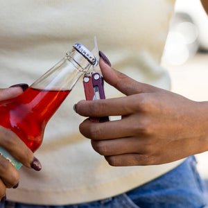 Translation missing: fr.A person using the bottle opener on a Mulled Wine Leatherman Micra® to open a glass bottle
